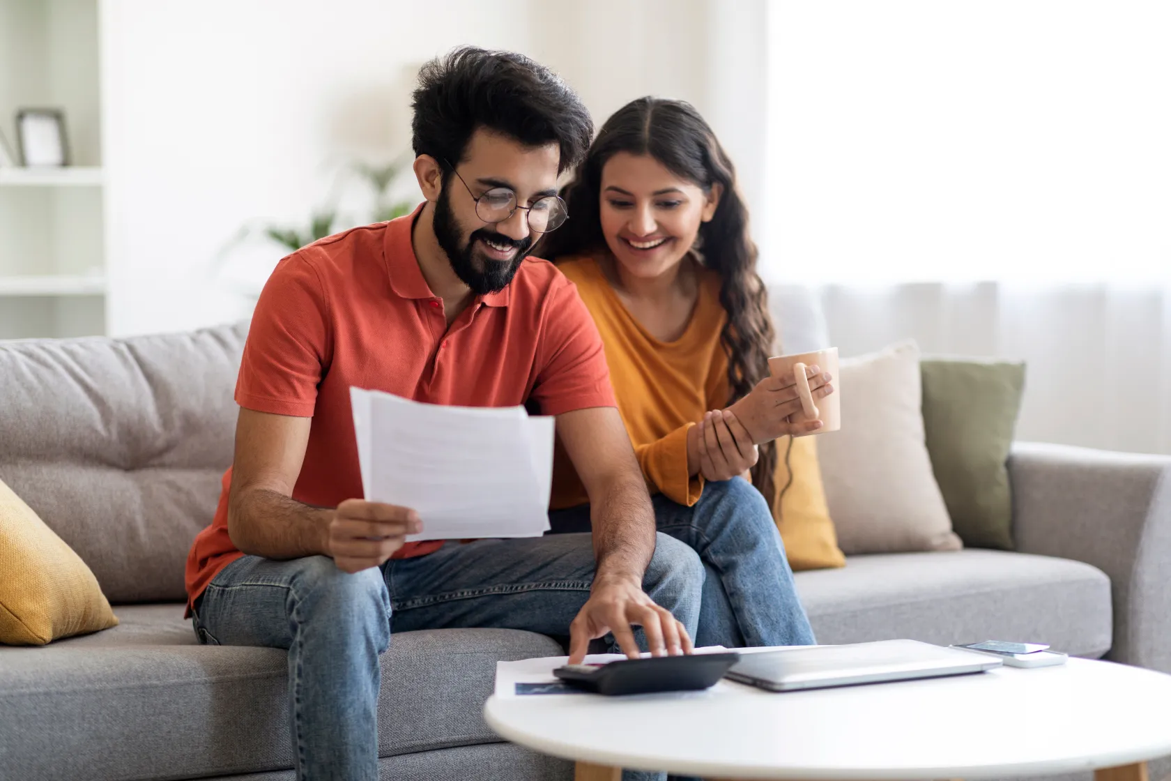 young-canadian-couple-reviewing-insurance-documents-at-kitchen-table-with-laptop-and-calculator